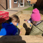 Zwei Mädchen spielen gemeinsam in der Sandkiste