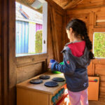 Kind spielt mit der Kinderküche im Außenbereich