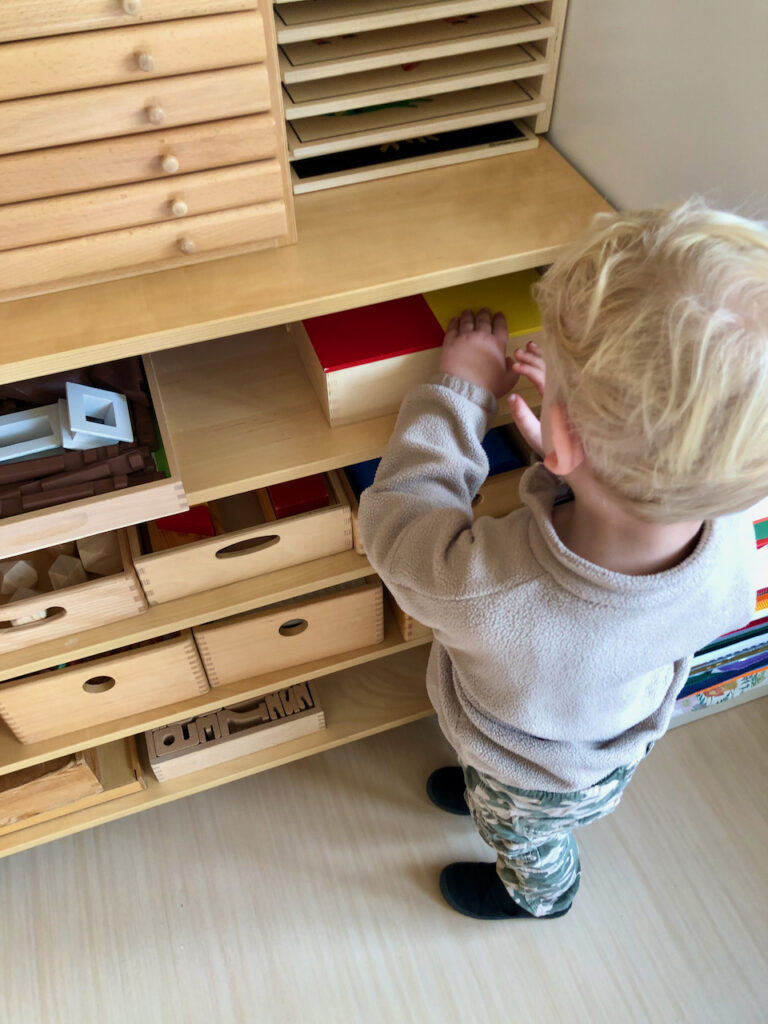Kind sucht sich eigenständig Spielzeug aus dem Montessorischrank