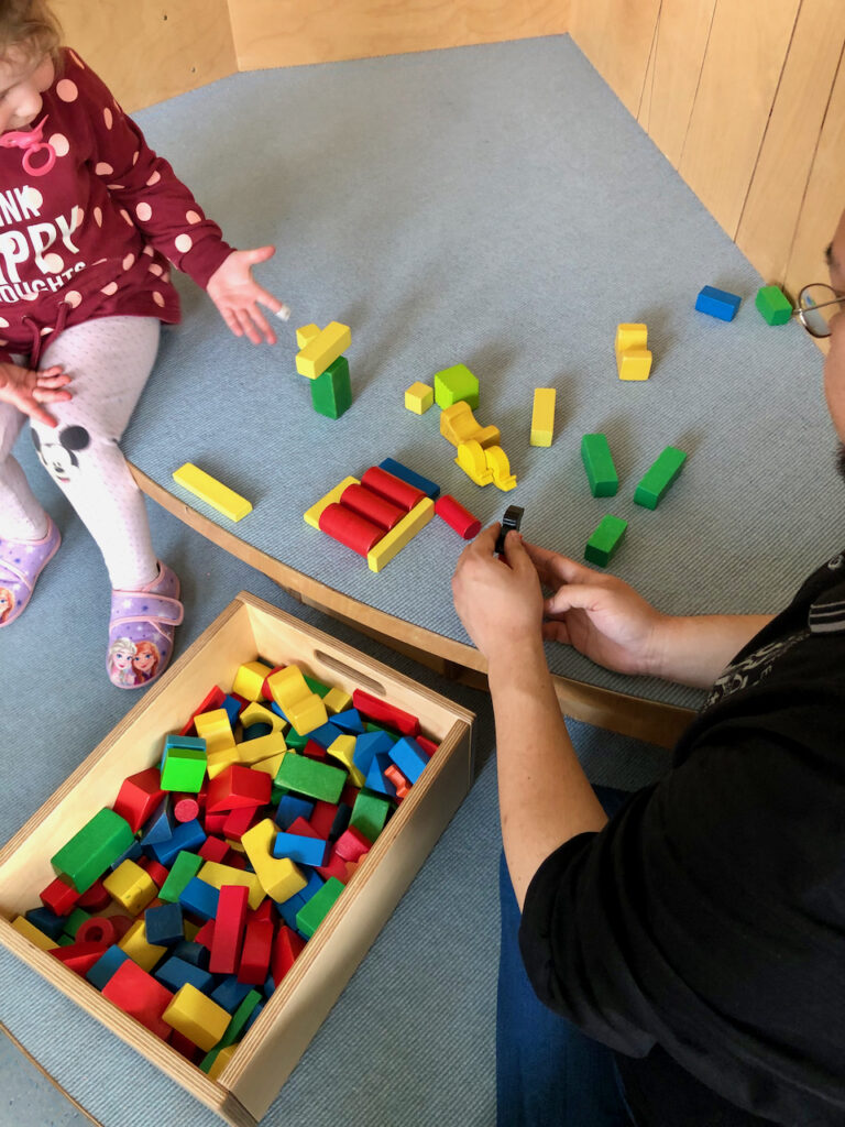 Kinderhände zeigen den erbauten Turm aus Bauklötzen