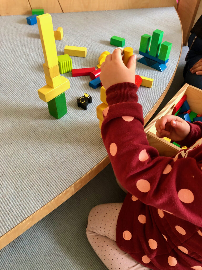 Kinderhand baut Turm aus Bauklötzen